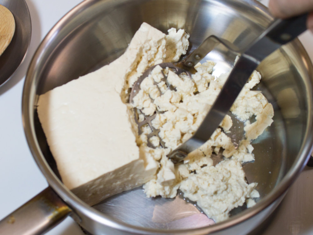 Tofu being mashed in saucepan