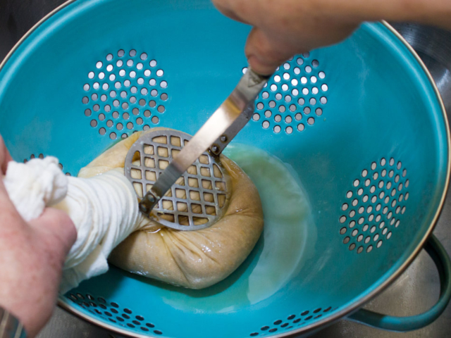 Join four corners of cloth and twist closed and press in colander to remove moisture.
