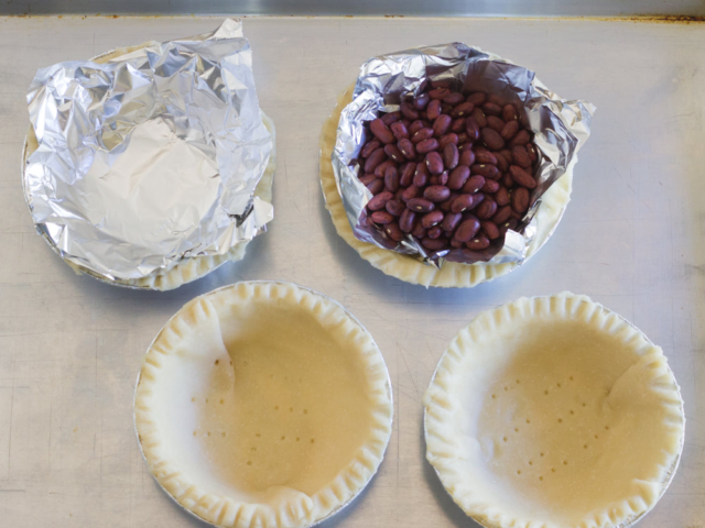 Filling tart pans with beans.