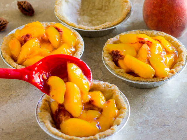 Spooning peaches into tart shells.