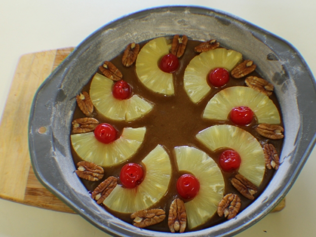 Arrange pineapple rings pecans maraschino cherries in bottom of pan