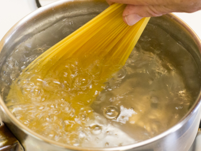 Adding angel hair pasta to pot of boiling water