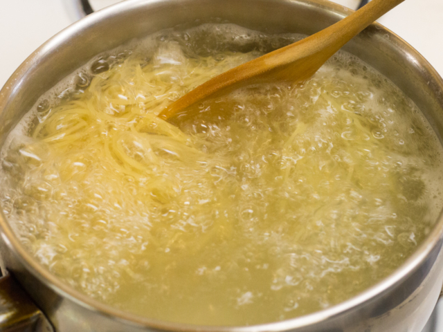 Angel hair pasta cooking in pot of boiling water.
