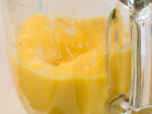 Lemon and tangerine fruit being mixed in blender.