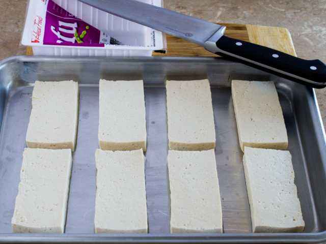 Eight slices fresh tofu on cookie sheet.
