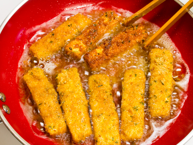Fish sticks in frying pan fried on the second side.