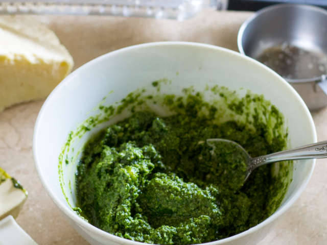 Parmesan cheese stirred into blended basil in bowl