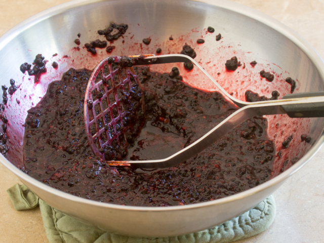 Blackberries mashed in a stainless steel bowl.