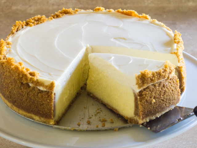 Baked and chilled cheesecake with one slice being removed.