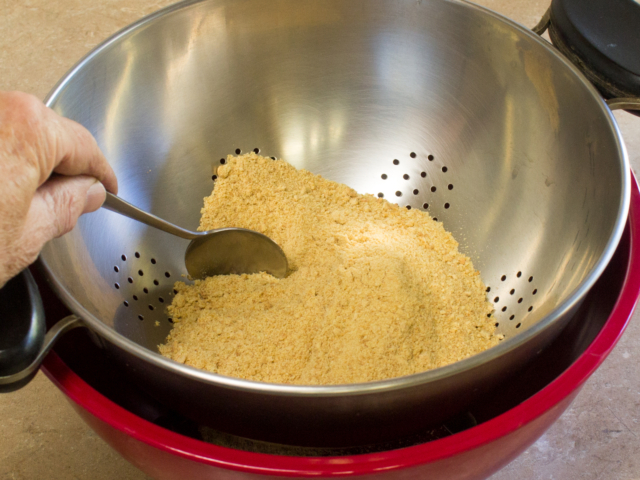Graham cracker crumbs sifted through colander and collected in bowl below to remove large pieces.