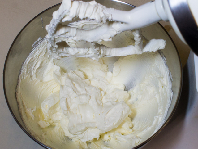 Cream cheese in mixer being beaten until creamy.