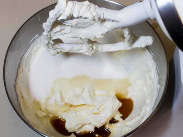 Sugar, lemon juice, vanilla flavoring, and salt added to cream cheese in mixing bowl.