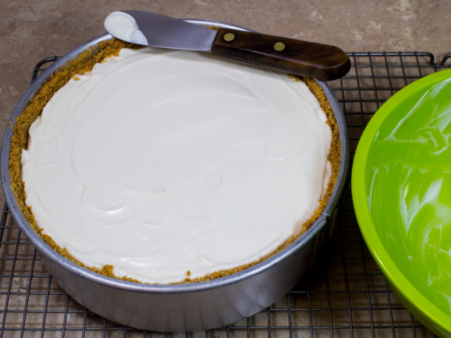 Finished cheesecake with sour cream mixture spread evenly over the top.