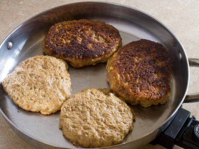 Four seitan steaks being fried in an e;electric skillet.