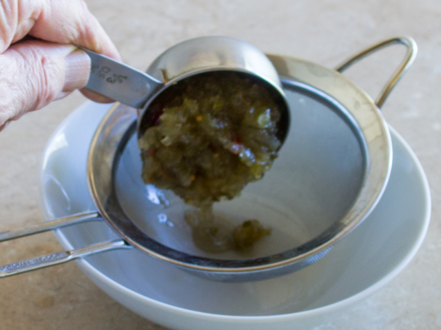One third cup sweet  relish placed in fine strainer over white bowl.