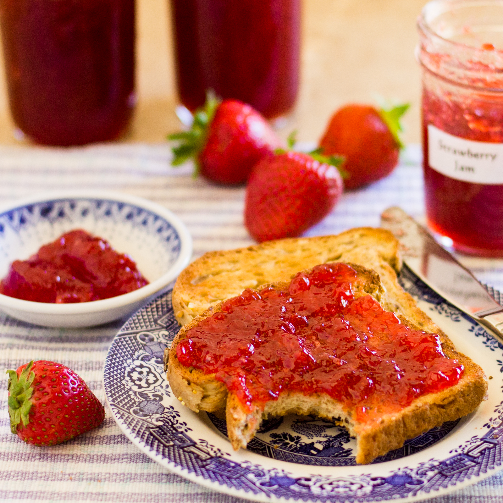 Two slice s of toast with strawberry jam spread on the top slice.