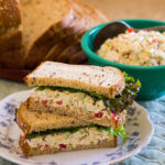 Vegetarian chicken sandwich on plate and bowl of chicken salad with slices ofbread